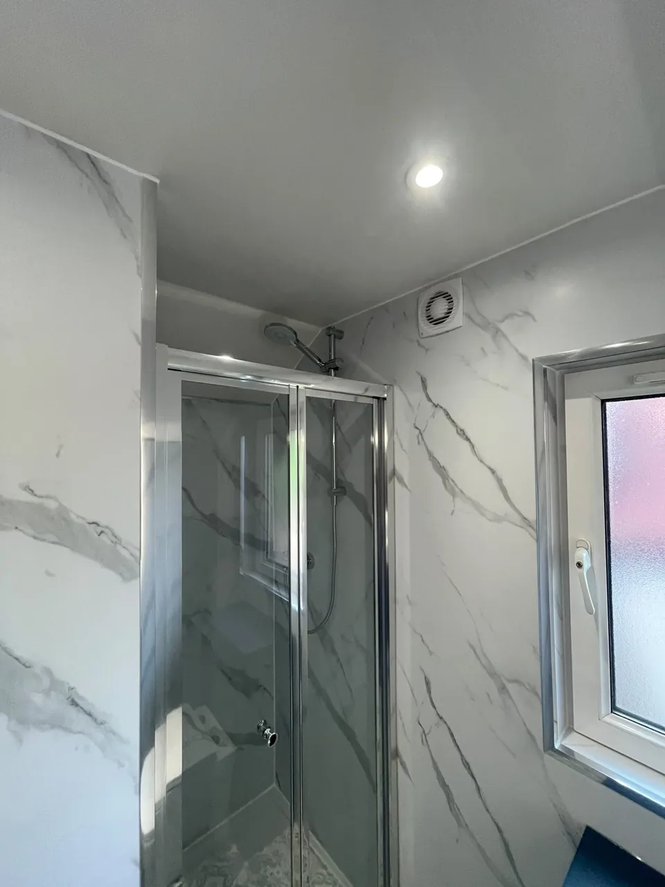 Glass shower enclosure and patterned bathroom flooring